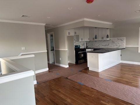 kitchen with electric range, kitchen peninsula, dark hardwood / wood-style floors, and decorative backsplash