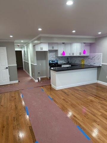 kitchen with hardwood / wood-style flooring, white cabinetry, kitchen peninsula, and decorative backsplash