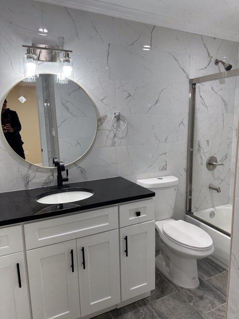 full bathroom featuring toilet,  shower combination, tile walls, and vanity