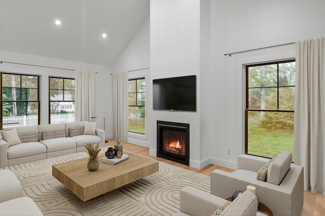 16 Hampton St, Westhampton Beach, NY 11978 - living room featuring high vaulted ceiling, light wood-style flooring, healthy amount of natural light, recessed lighting, and a glass covered fireplace