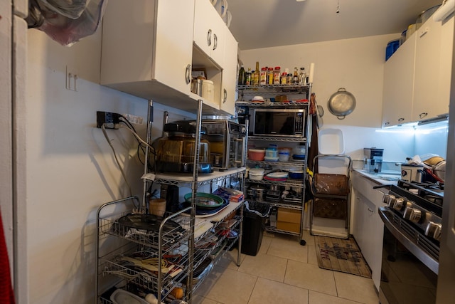 kitchen featuring built in microwave, white cabinetry, light tile patterned flooring, and gas stove