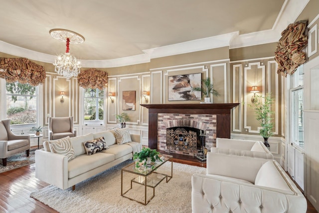 living room with crown molding, a chandelier, hardwood / wood-style floors, and a brick fireplace