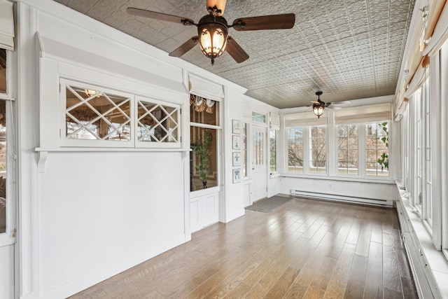 unfurnished sunroom with ceiling fan and baseboard heating