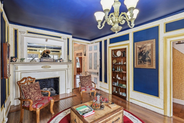 living room with dark wood-type flooring, a fireplace, a chandelier, and built in shelves