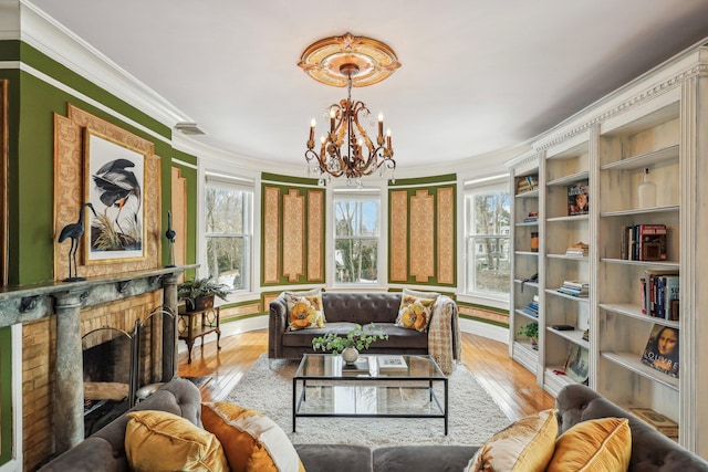 living room featuring crown molding, a fireplace, a chandelier, and light wood-type flooring