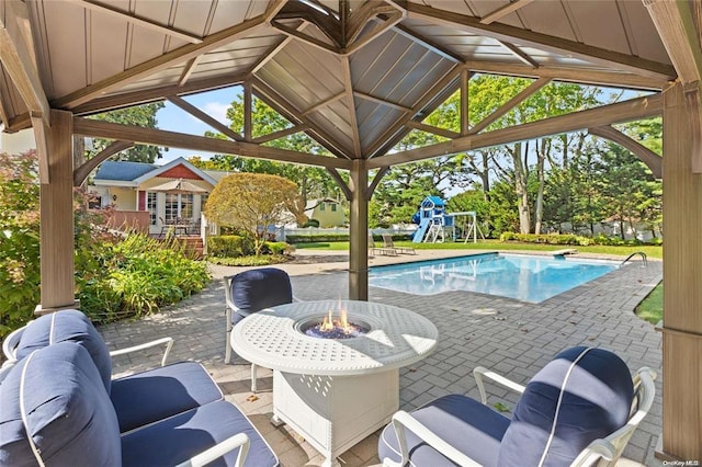 pool with a patio, an outdoor fire pit, and playground community