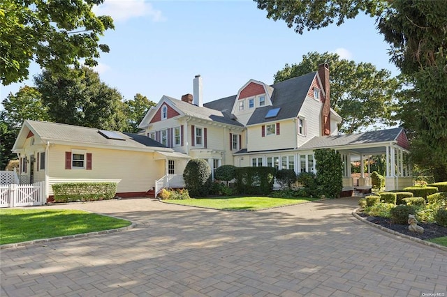 view of front of house featuring fence, decorative driveway, a front yard, a gate, and a chimney