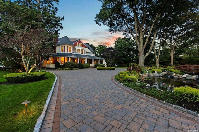 view of front of home with curved driveway and a yard