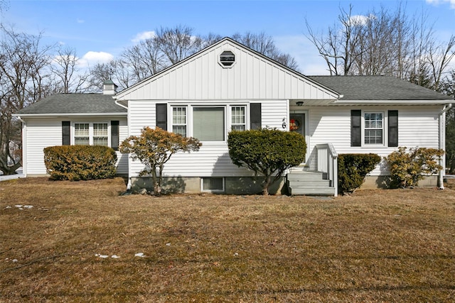 view of front of property featuring a shingled roof, a front yard, and a chimney