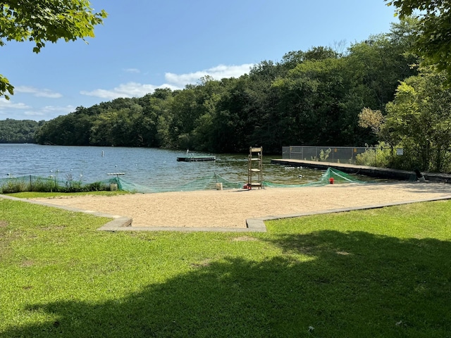 view of community with a forest view, a lawn, and a water view