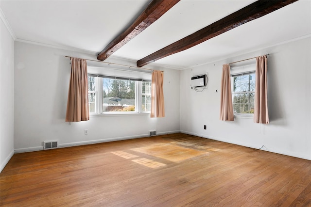 spare room with a wealth of natural light, visible vents, and wood finished floors