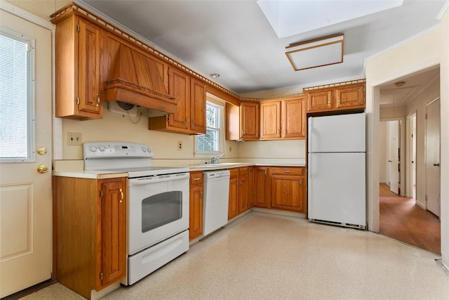 kitchen with brown cabinets, light countertops, white appliances, and premium range hood