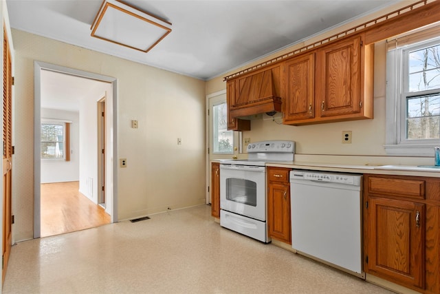 kitchen featuring white appliances, a wealth of natural light, and brown cabinets