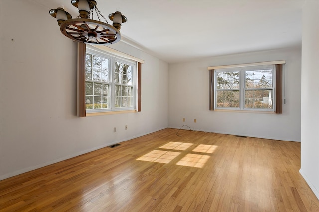 empty room featuring visible vents, plenty of natural light, and light wood finished floors