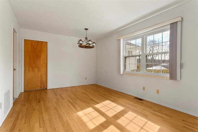 unfurnished room featuring light wood-style flooring, visible vents, and a chandelier