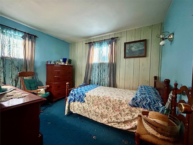 carpeted bedroom featuring wood walls