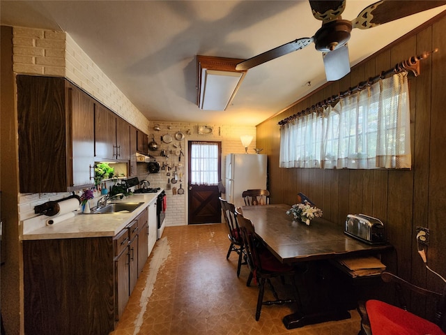 dining room featuring ceiling fan, brick wall, and sink