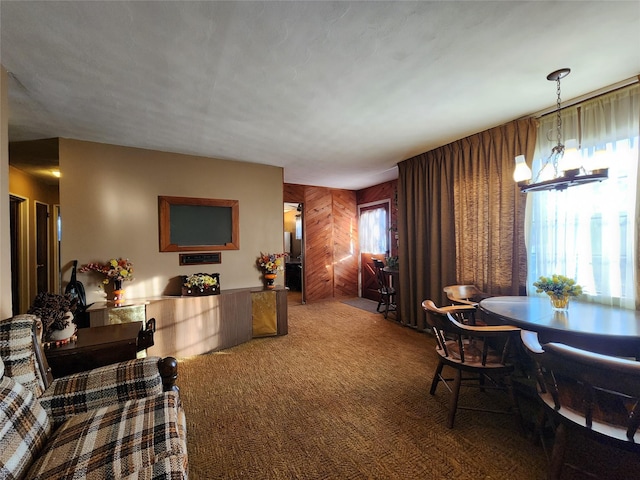 dining room with carpet flooring, a notable chandelier, and wood walls