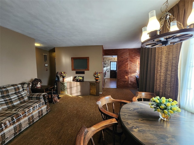 carpeted living room featuring a notable chandelier and wood walls