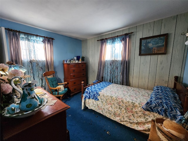 bedroom with dark colored carpet and wood walls