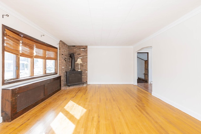 unfurnished living room featuring light hardwood / wood-style floors, a wood stove, and ornamental molding