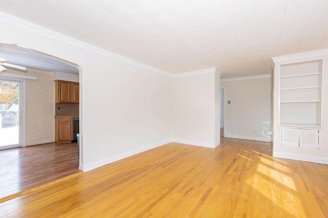 empty room featuring built in features, light hardwood / wood-style flooring, and crown molding