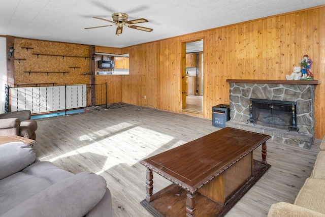 living room featuring light wood-type flooring, ceiling fan, wood walls, and a fireplace