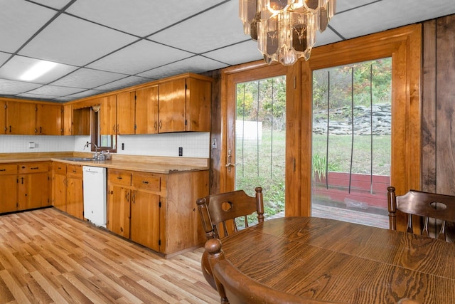 kitchen with sink, dishwasher, light hardwood / wood-style floors, and backsplash