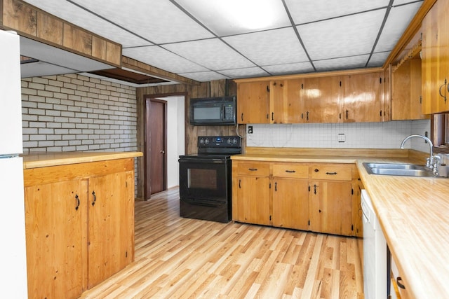 kitchen featuring black appliances, tasteful backsplash, sink, light wood-type flooring, and a drop ceiling