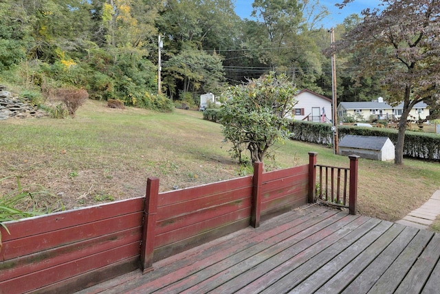 wooden deck featuring a storage unit and a lawn