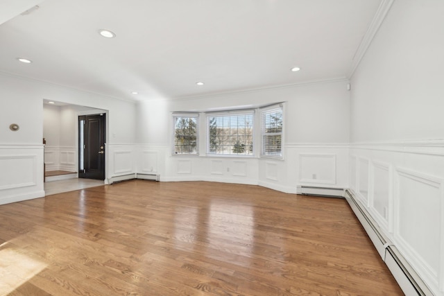 spare room featuring crown molding, light wood-type flooring, and a baseboard heating unit