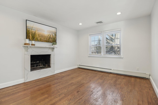 unfurnished living room with hardwood / wood-style flooring and a baseboard radiator