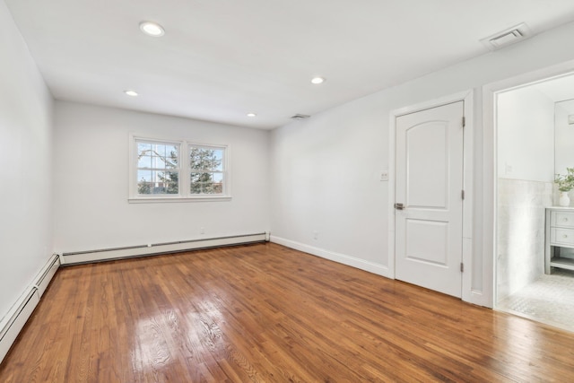 unfurnished room with hardwood / wood-style flooring and baseboard heating