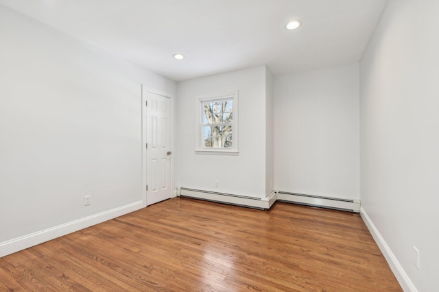 unfurnished room with a baseboard radiator and hardwood / wood-style floors