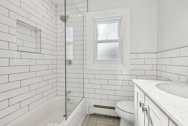 full bathroom with a baseboard radiator, tile walls, tiled shower / bath combo, toilet, and vanity