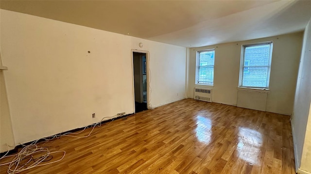 spare room featuring radiator heating unit and light hardwood / wood-style flooring