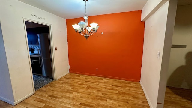 unfurnished dining area featuring light hardwood / wood-style flooring and a chandelier