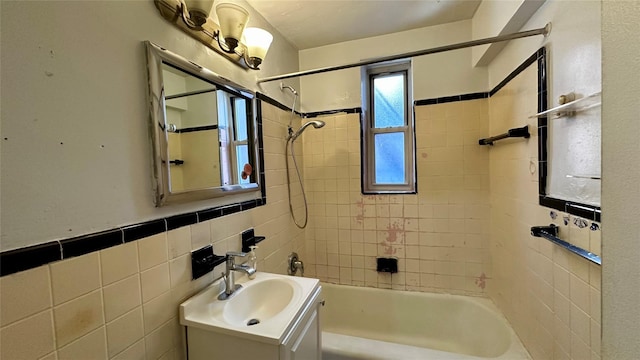 bathroom featuring tiled shower / bath, vanity, and tile walls