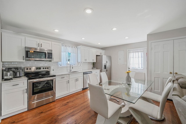 kitchen featuring dark hardwood / wood-style floors, tasteful backsplash, sink, white cabinets, and stainless steel appliances