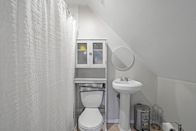 bathroom with lofted ceiling, toilet, and a shower with shower curtain