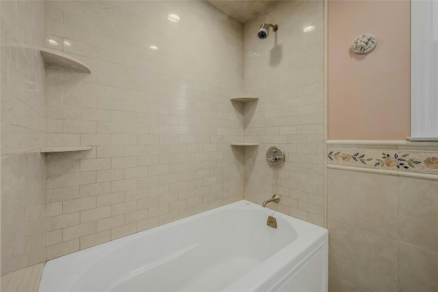 bathroom with tiled shower / bath combo and tile walls