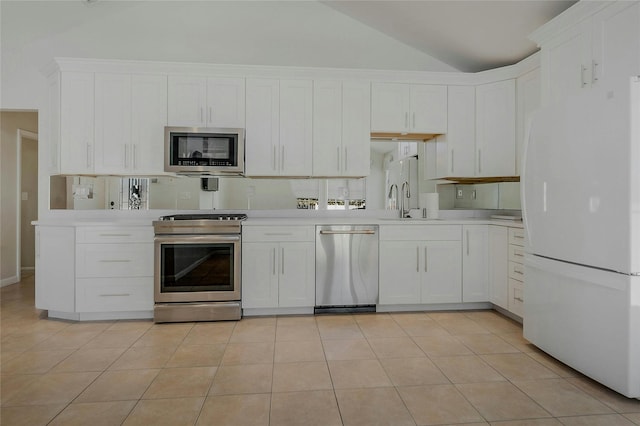 kitchen with lofted ceiling, light tile patterned floors, white cabinets, and appliances with stainless steel finishes