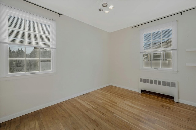 spare room featuring radiator and hardwood / wood-style floors