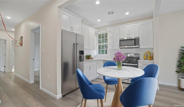 kitchen with light hardwood / wood-style floors, white cabinetry, and stainless steel appliances