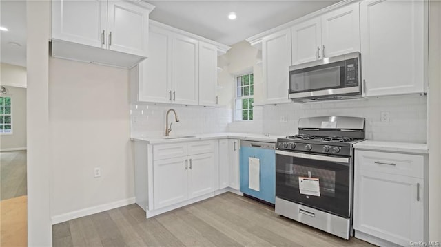 kitchen featuring white cabinets, appliances with stainless steel finishes, sink, and light hardwood / wood-style flooring