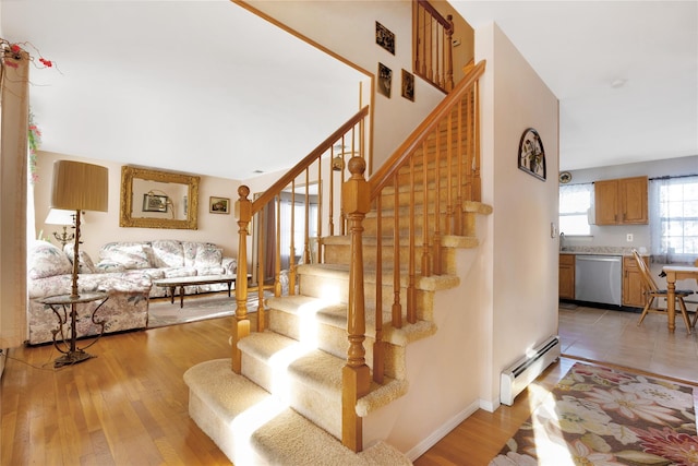 stairway with baseboard heating and hardwood / wood-style floors