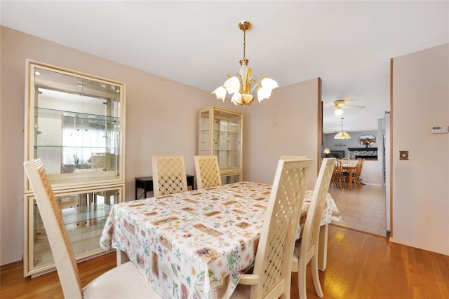 dining space with hardwood / wood-style flooring and ceiling fan with notable chandelier