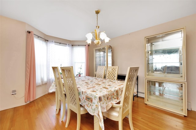 dining space featuring baseboard heating, light hardwood / wood-style floors, and a notable chandelier