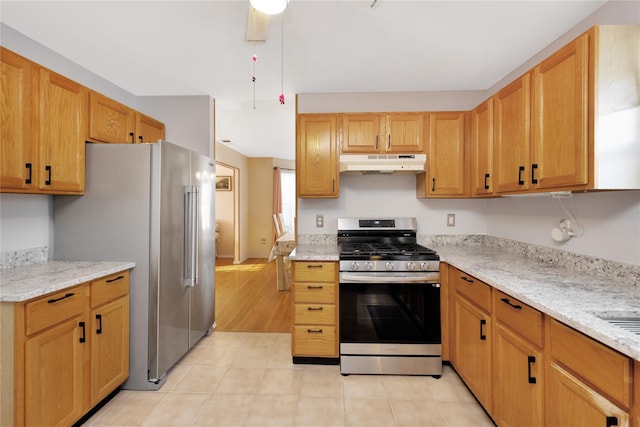 kitchen featuring stainless steel appliances, ceiling fan, and light stone countertops