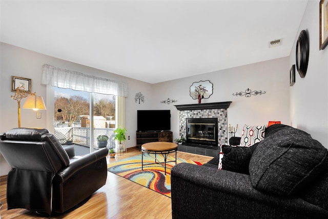 living room featuring a tile fireplace and hardwood / wood-style flooring